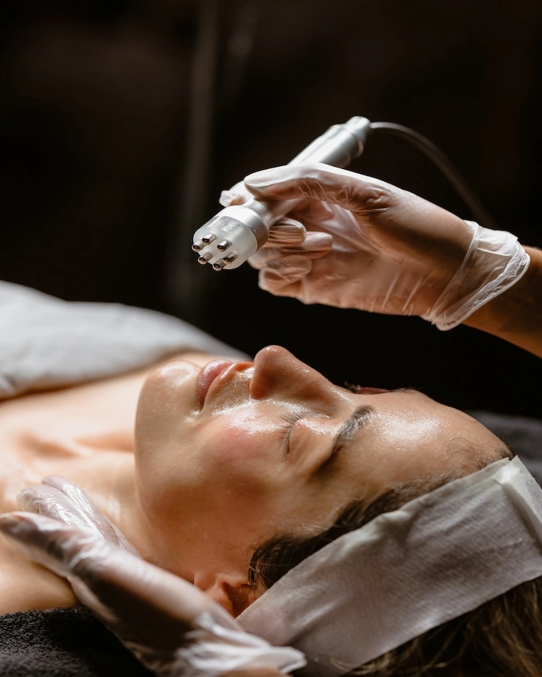 A person receiving a facial treatment using a specialized skincare device by Alexandrian based estheticians.